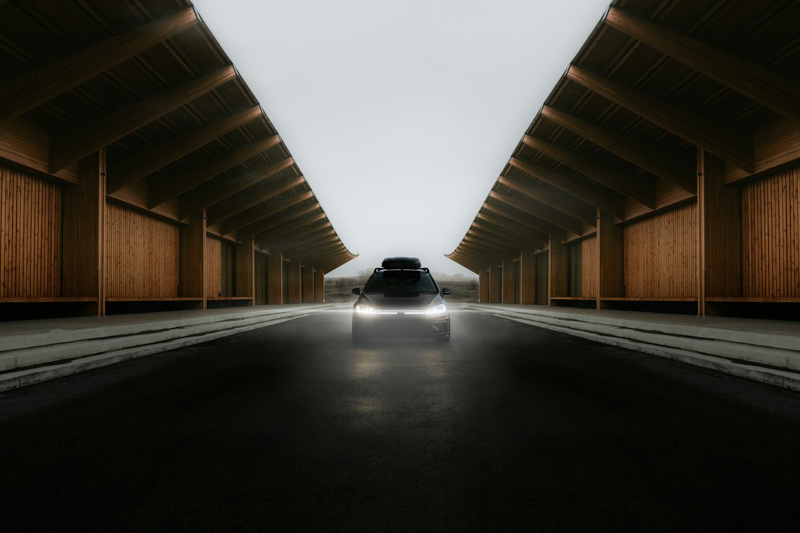A car approaches through a wooden structure.